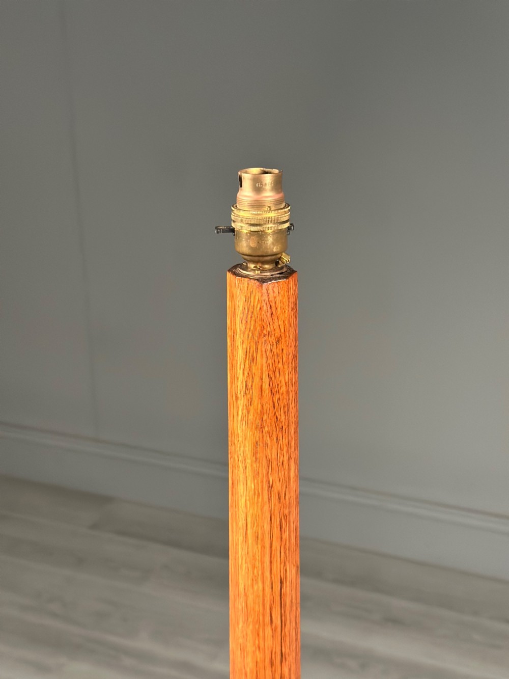 A tall Arts and Crafts solid oak standard lamp featuring a faceted stem mounted on an octagonal base with a brass light socket. View VI