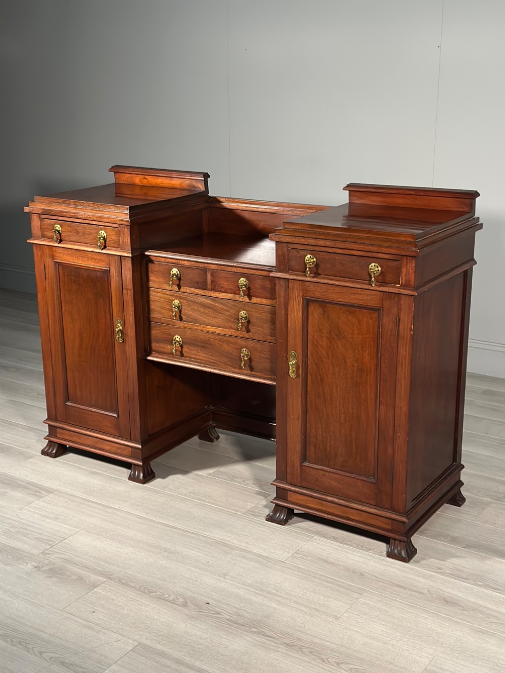 An Edwardian mahogany pedestal sideboard featuring two outer pedestal cupboards, central drawers, and brass drop handles. View II