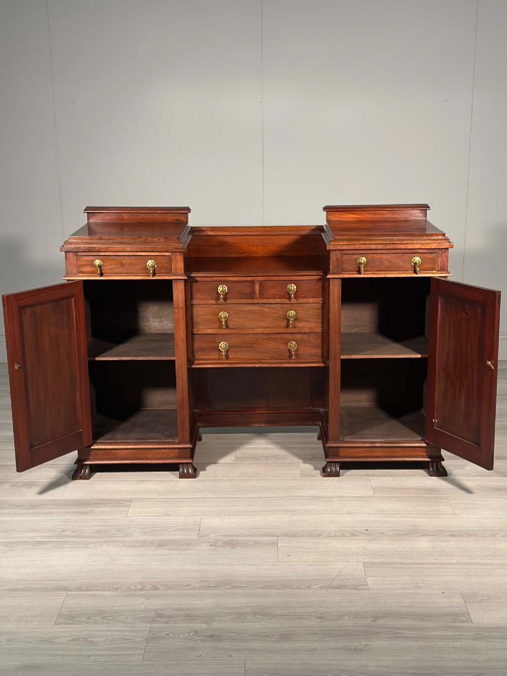An Edwardian mahogany pedestal sideboard featuring two outer pedestal cupboards, central drawers, and brass drop handles. View III