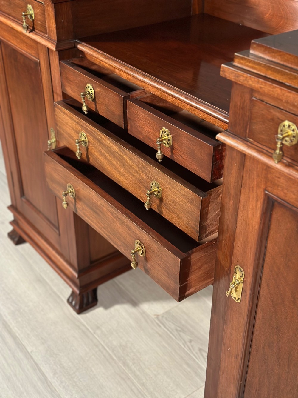 An Edwardian mahogany pedestal sideboard featuring two outer pedestal cupboards, central drawers, and brass drop handles. View V
