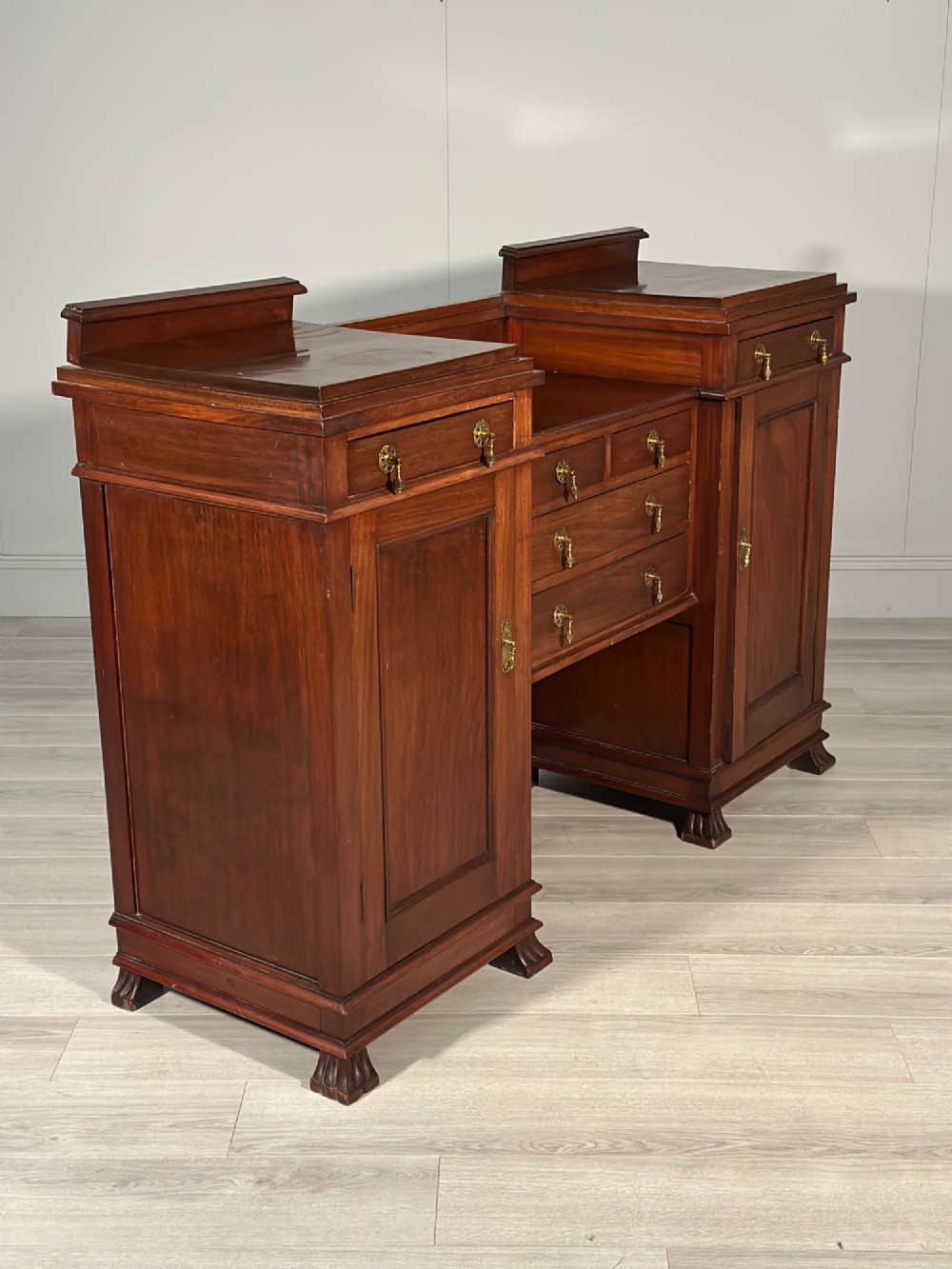 An Edwardian mahogany pedestal sideboard featuring two outer pedestal cupboards, central drawers, and brass drop handles. View VII