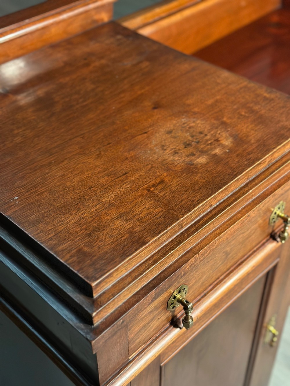 An Edwardian mahogany pedestal sideboard featuring two outer pedestal cupboards, central drawers, and brass drop handles. View X