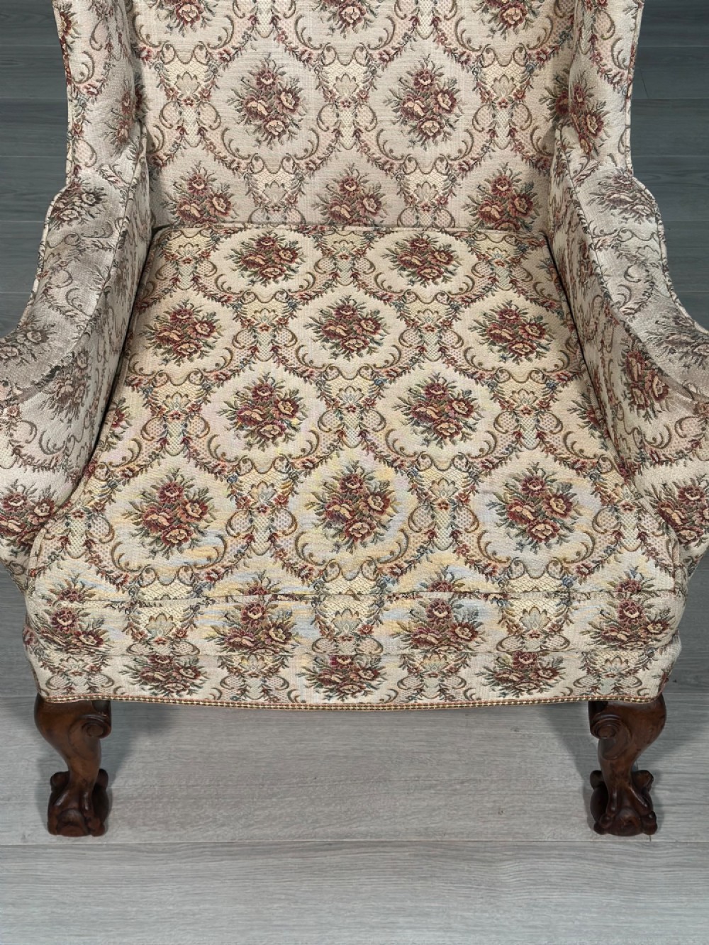 An Edwardian wingback armchair upholstered in cream floral patterned fabric with carved mahogany cabriole legs and ball-and-claw feet. View II