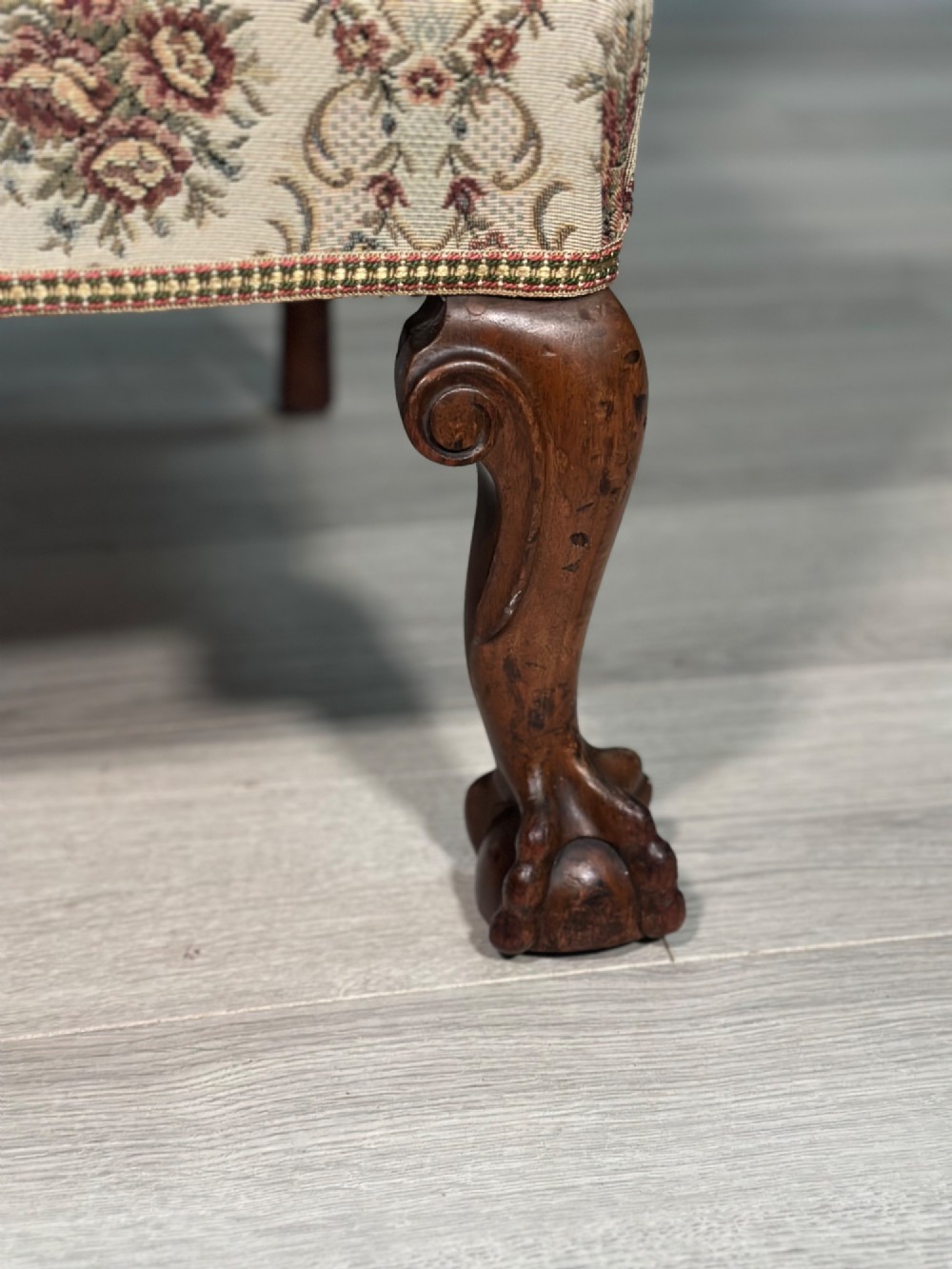 An Edwardian wingback armchair upholstered in cream floral patterned fabric with carved mahogany cabriole legs and ball-and-claw feet. View III
