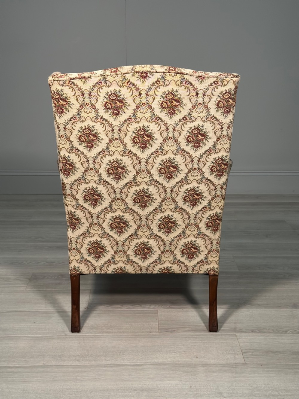 An Edwardian wingback armchair upholstered in cream floral patterned fabric with carved mahogany cabriole legs and ball-and-claw feet. View VI