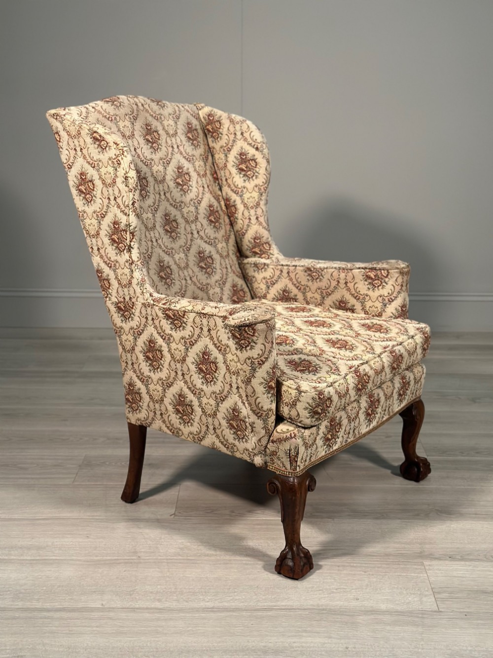 An Edwardian wingback armchair upholstered in cream floral patterned fabric with carved mahogany cabriole legs and ball-and-claw feet. View VII