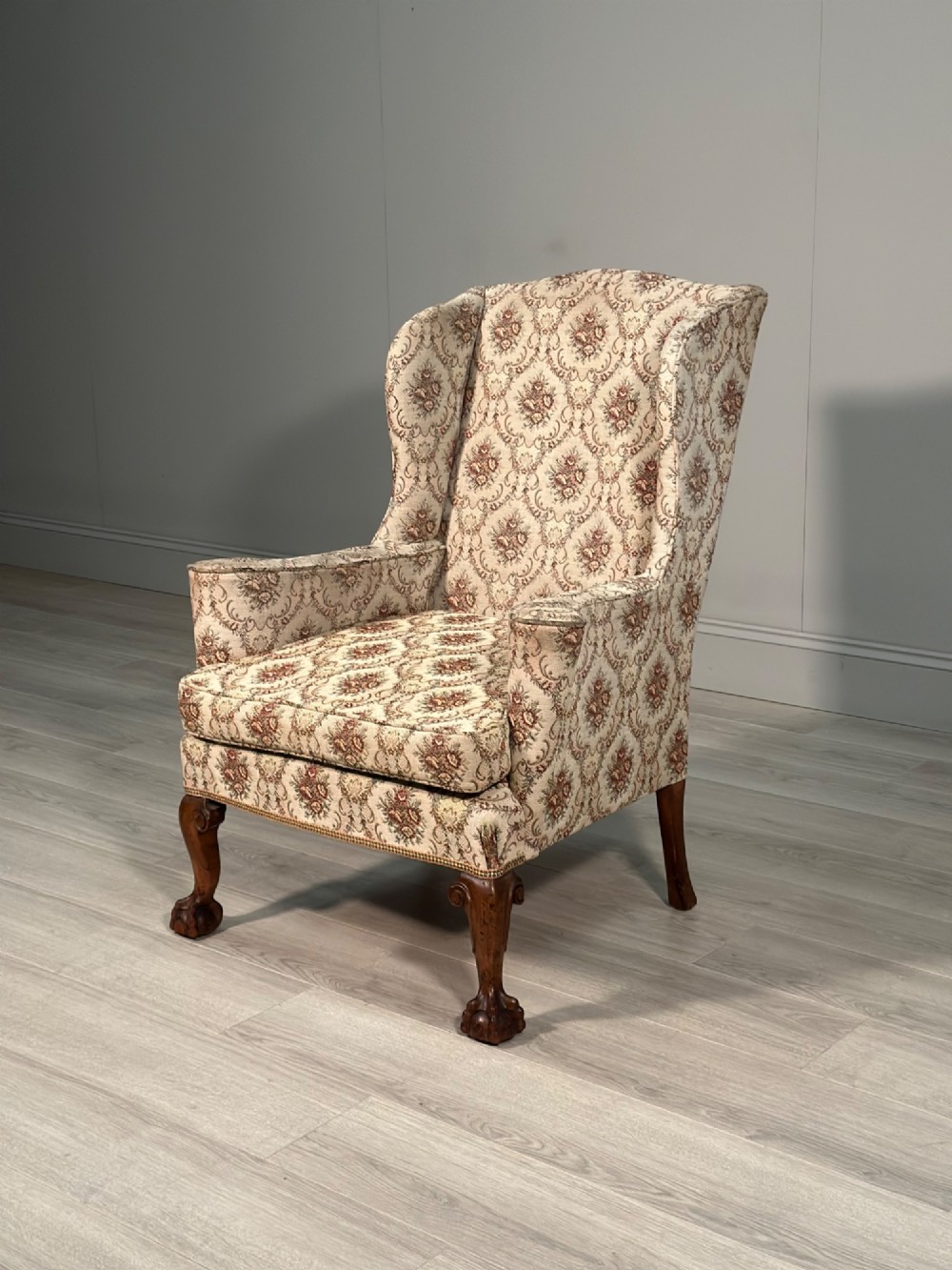 An Edwardian wingback armchair upholstered in cream floral patterned fabric with carved mahogany cabriole legs and ball-and-claw feet. View XI
