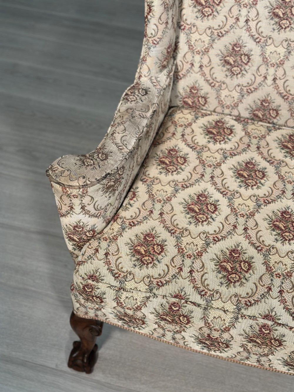 An Edwardian wingback armchair upholstered in cream floral patterned fabric with carved mahogany cabriole legs and ball-and-claw feet. View XII