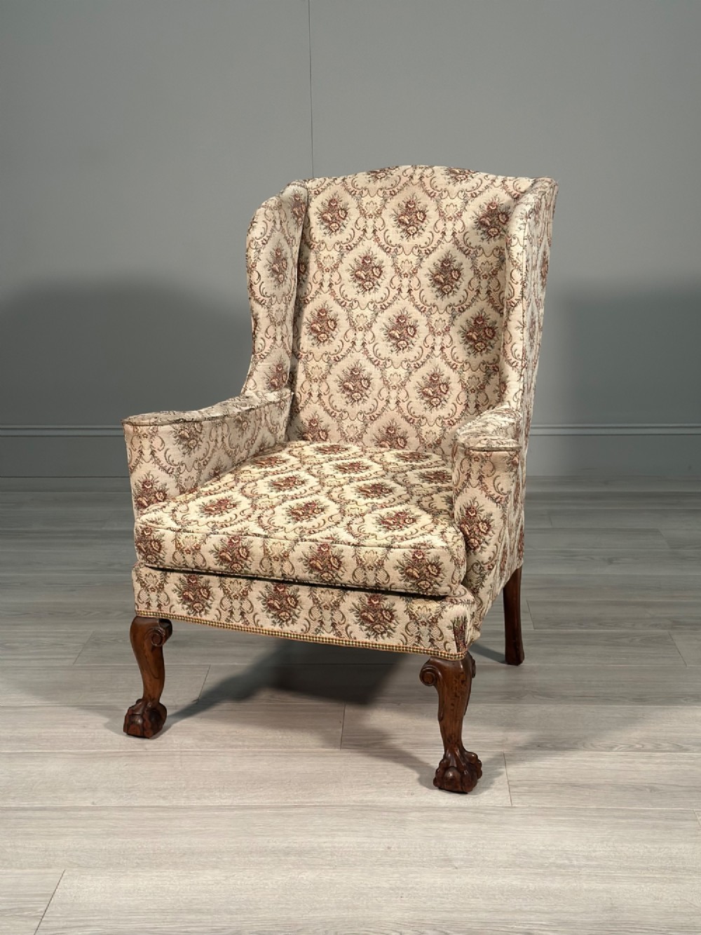 An Edwardian wingback armchair upholstered in cream floral patterned fabric with carved mahogany cabriole legs and ball-and-claw feet. View XIV