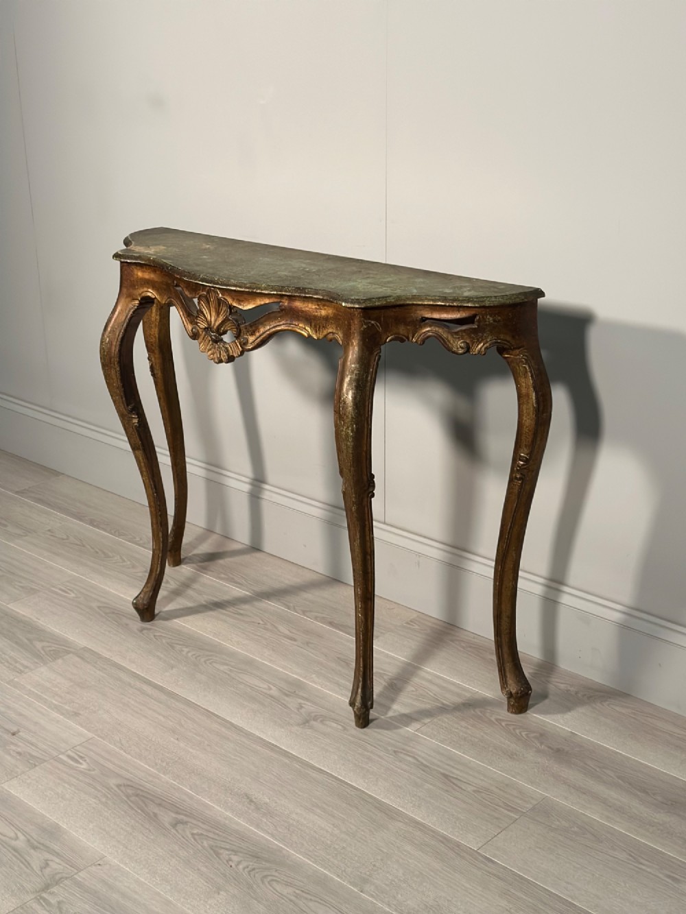 A Rococo style carved giltwood console table featuring cabriole legs, central shell motif, serpentine apron, and a dark marble top. View II