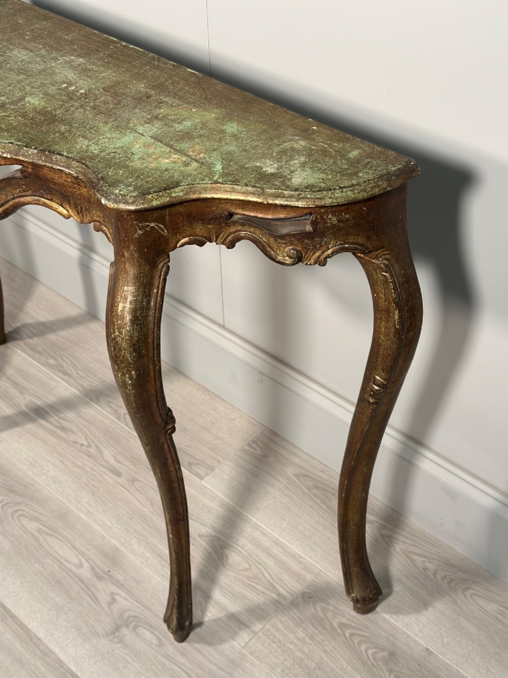 A Rococo style carved giltwood console table featuring cabriole legs, central shell motif, serpentine apron, and a dark marble top. View III