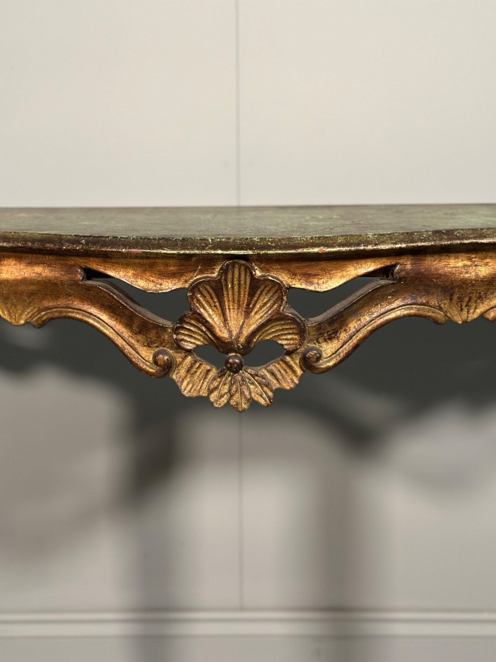 A Rococo style carved giltwood console table featuring cabriole legs, central shell motif, serpentine apron, and a dark marble top. View IV