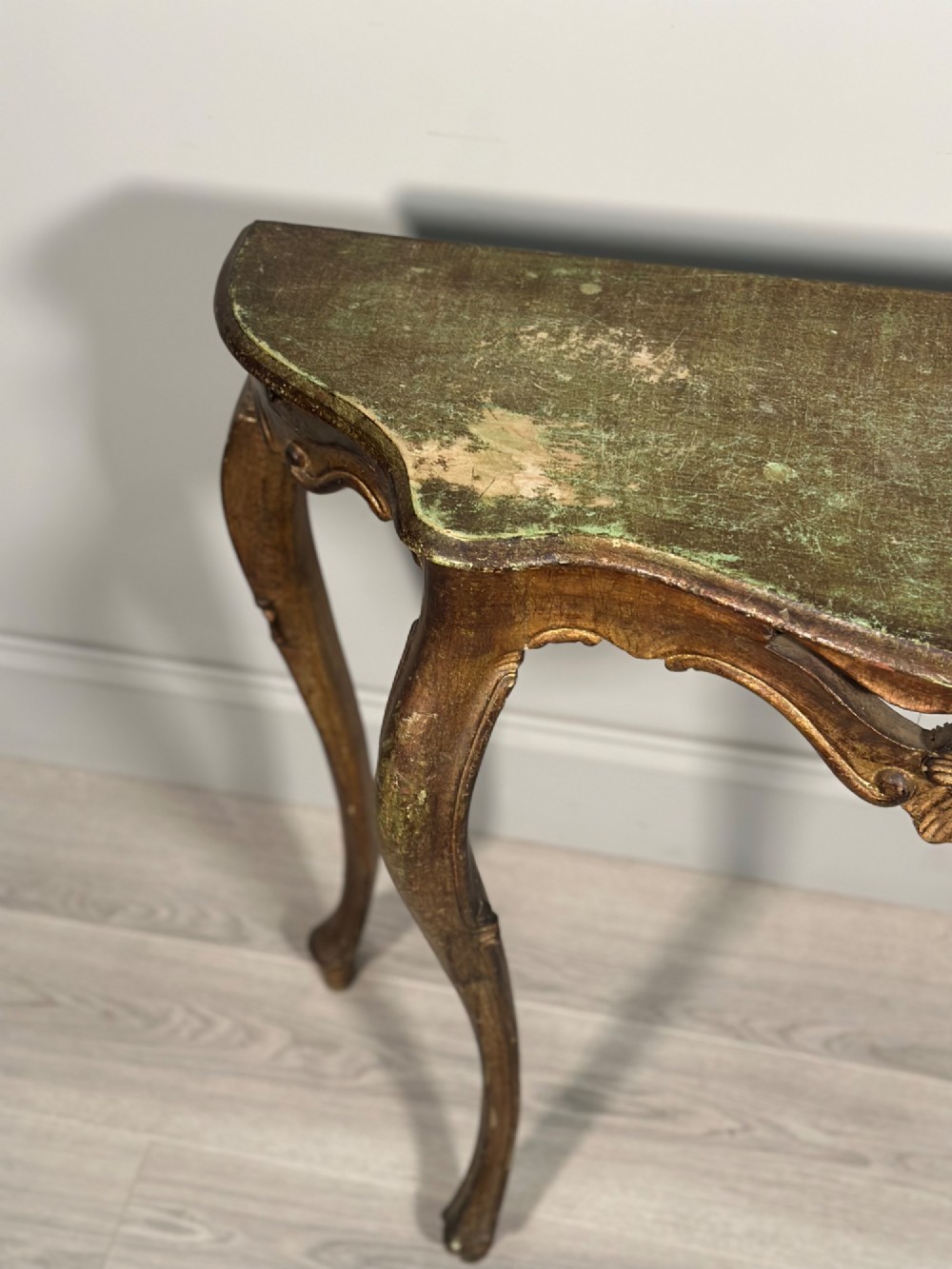 A Rococo style carved giltwood console table featuring cabriole legs, central shell motif, serpentine apron, and a dark marble top. View V