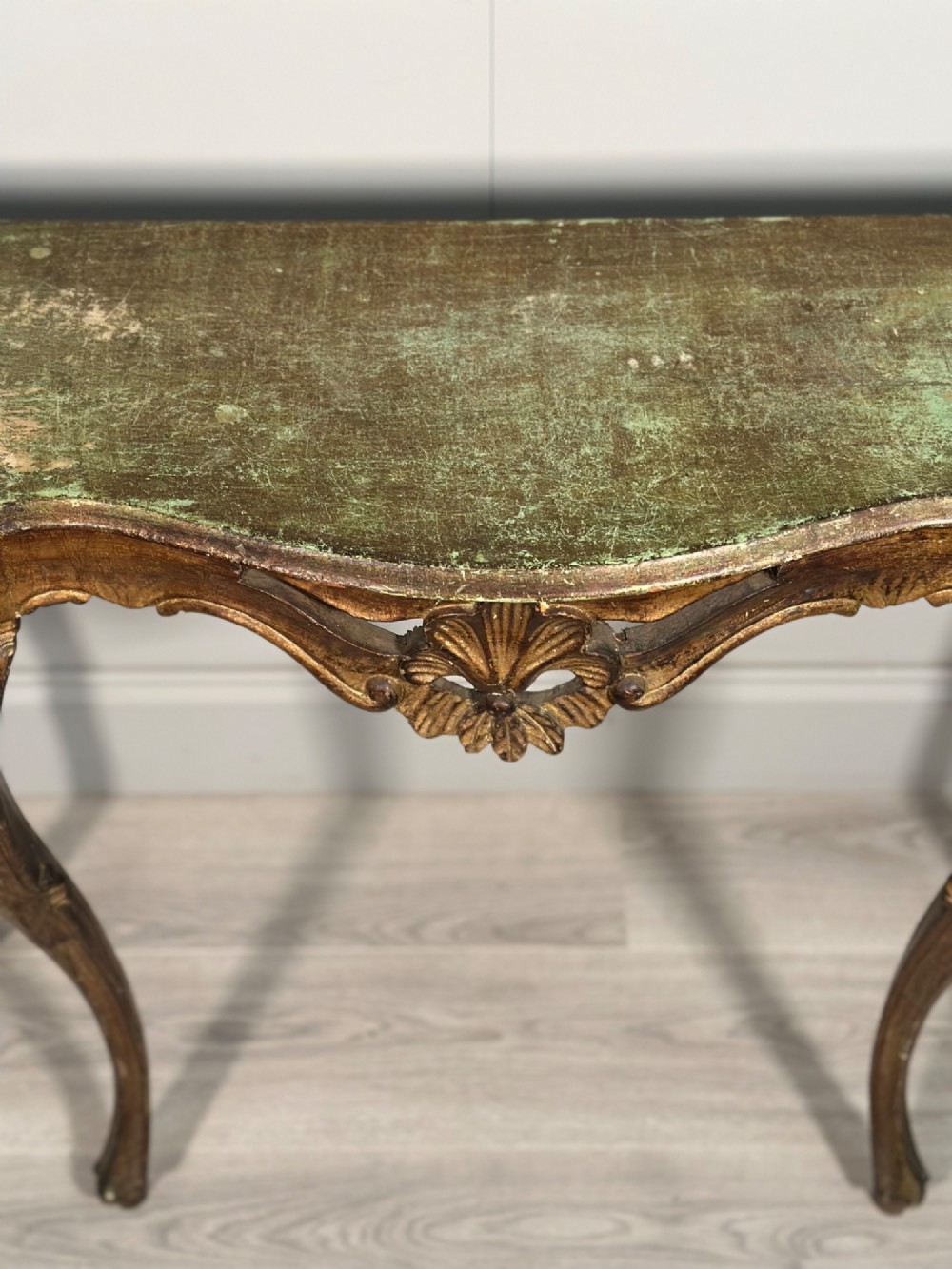 A Rococo style carved giltwood console table featuring cabriole legs, central shell motif, serpentine apron, and a dark marble top. View VI