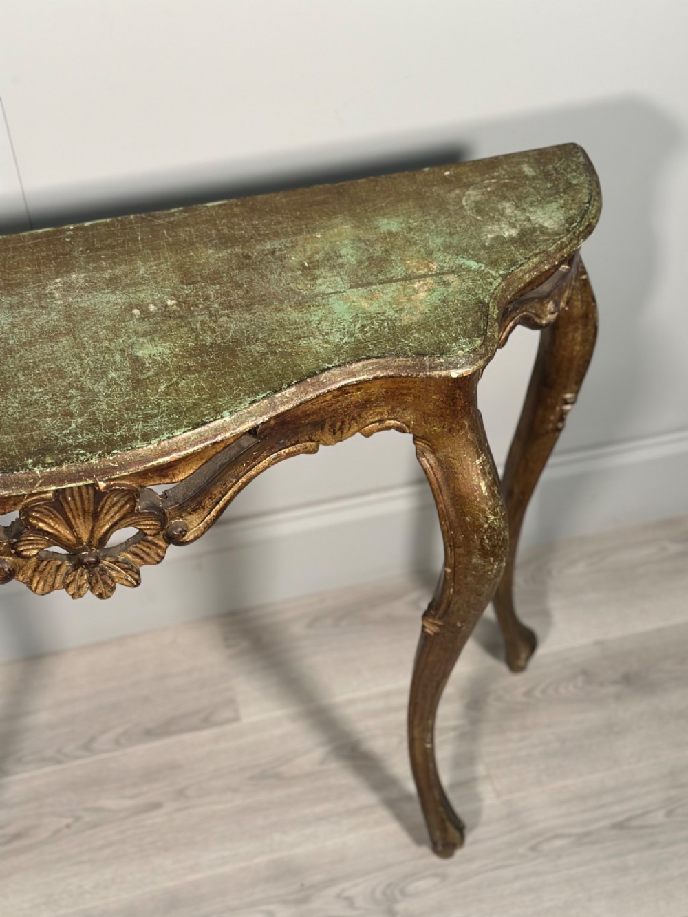 A Rococo style carved giltwood console table featuring cabriole legs, central shell motif, serpentine apron, and a dark marble top. View VII