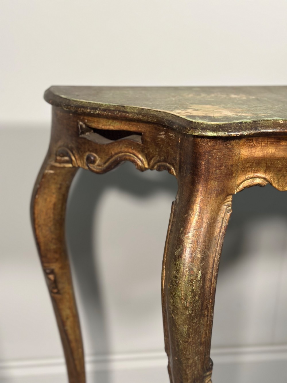 A Rococo style carved giltwood console table featuring cabriole legs, central shell motif, serpentine apron, and a dark marble top. View VIII