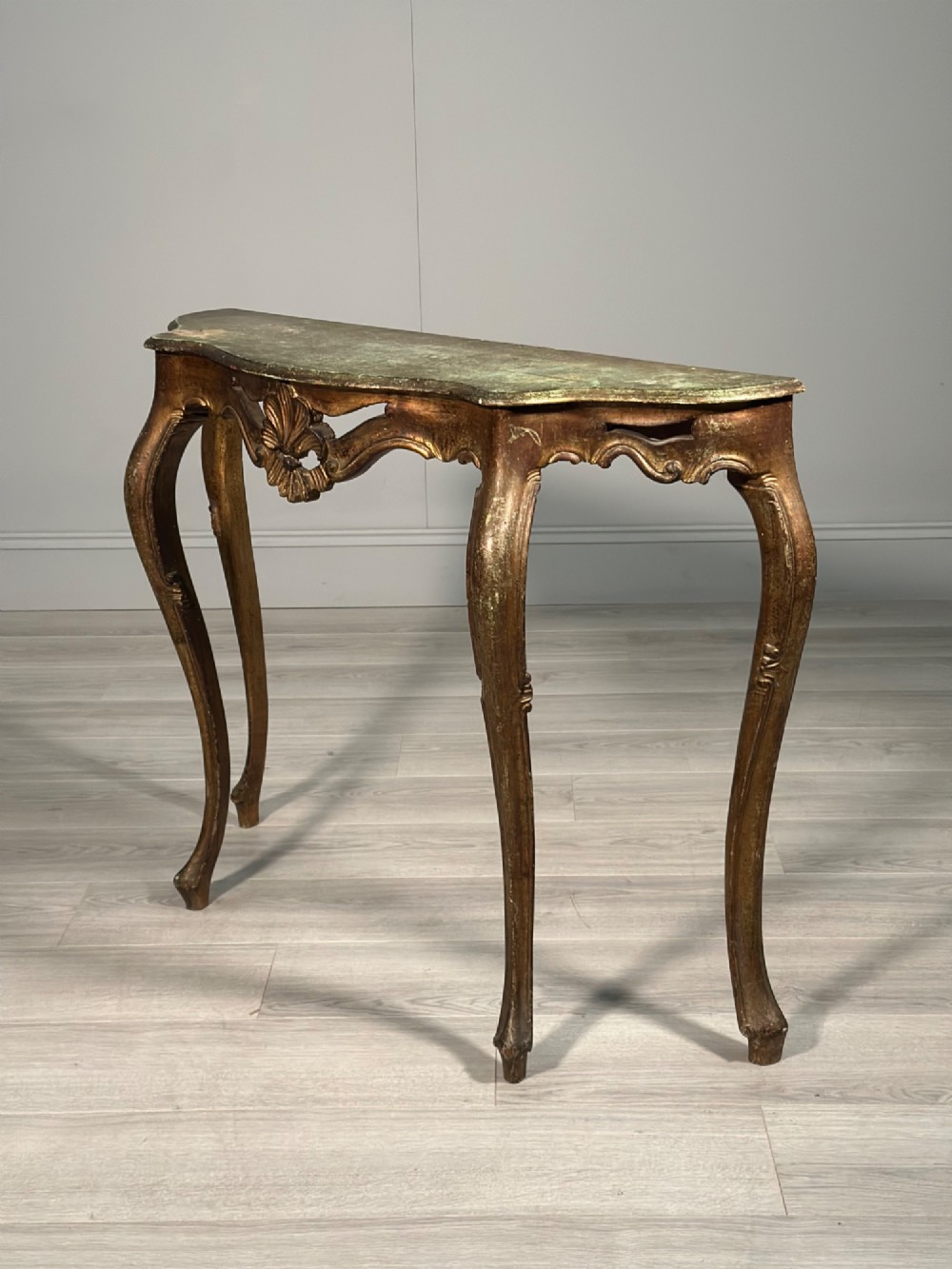 A Rococo style carved giltwood console table featuring cabriole legs, central shell motif, serpentine apron, and a dark marble top. View XI