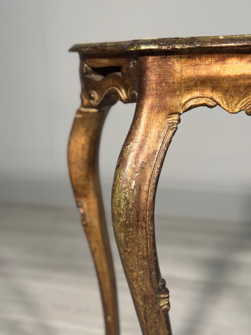 A Rococo style carved giltwood console table featuring cabriole legs, central shell motif, serpentine apron, and a dark marble top. View XV