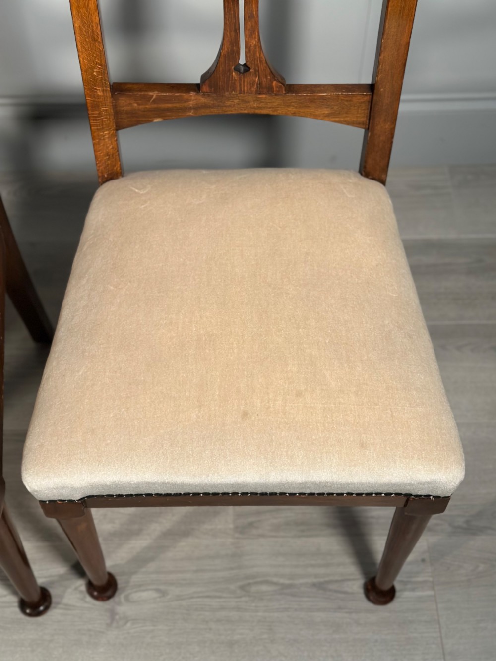 A set of four antique Biedermeier dining chairs featuring carved wooden frames, pierced back splats, and cream upholstered seats with brass stud detailing. View V