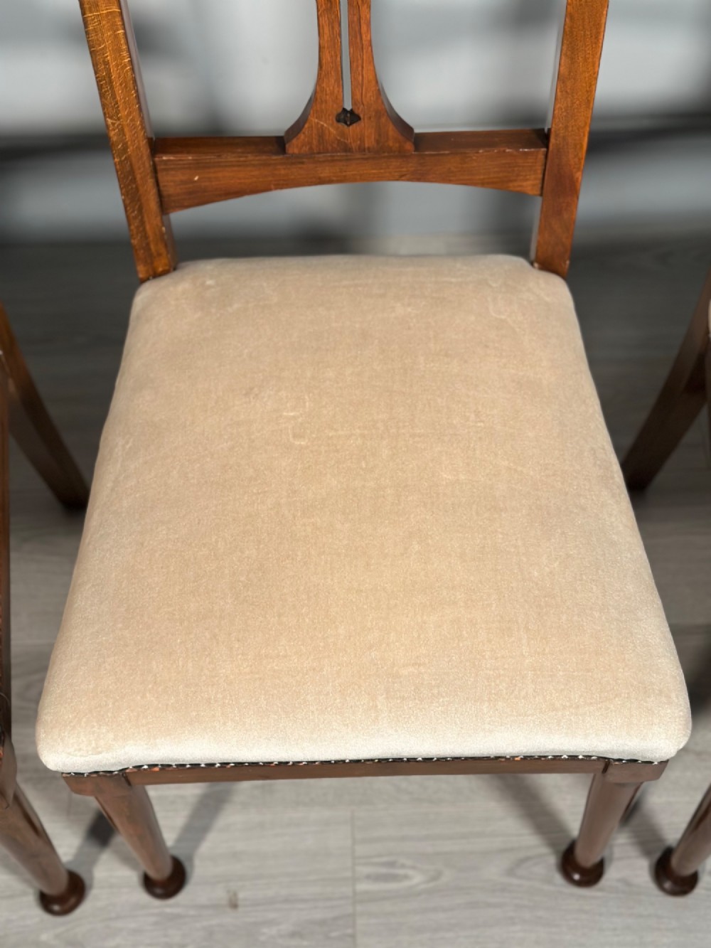 A set of four antique Biedermeier dining chairs featuring carved wooden frames, pierced back splats, and cream upholstered seats with brass stud detailing. View VII