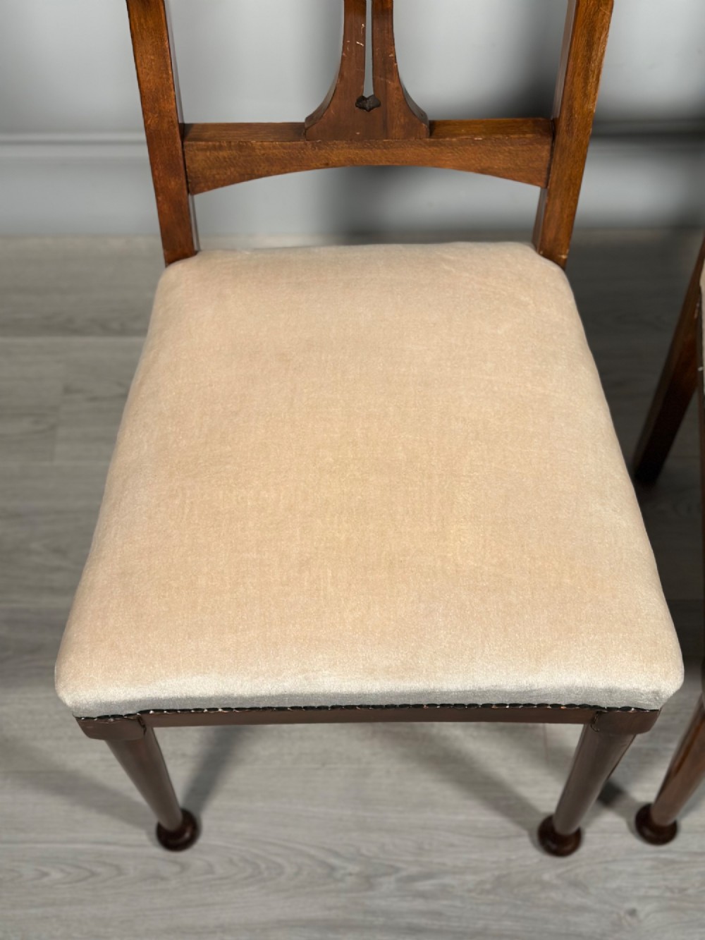 A set of four antique Biedermeier dining chairs featuring carved wooden frames, pierced back splats, and cream upholstered seats with brass stud detailing. View VIII
