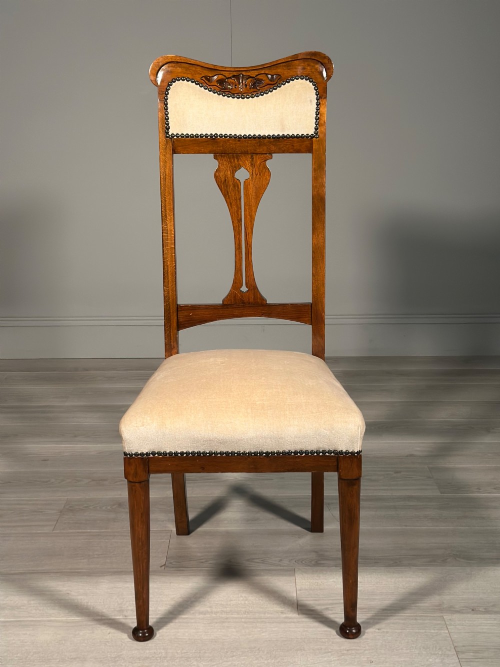 A set of four antique Biedermeier dining chairs featuring carved wooden frames, pierced back splats, and cream upholstered seats with brass stud detailing. View XII