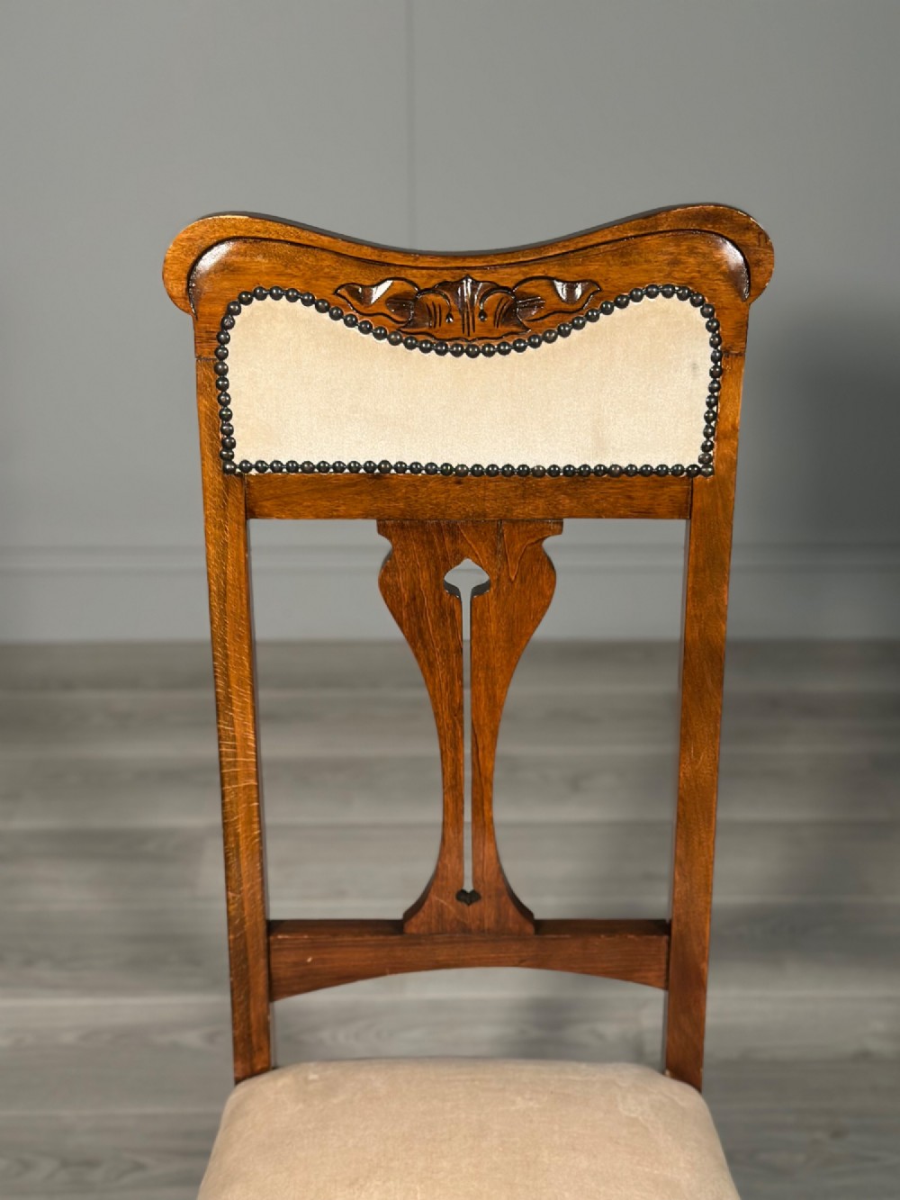 A set of four antique Biedermeier dining chairs featuring carved wooden frames, pierced back splats, and cream upholstered seats with brass stud detailing. View XIII