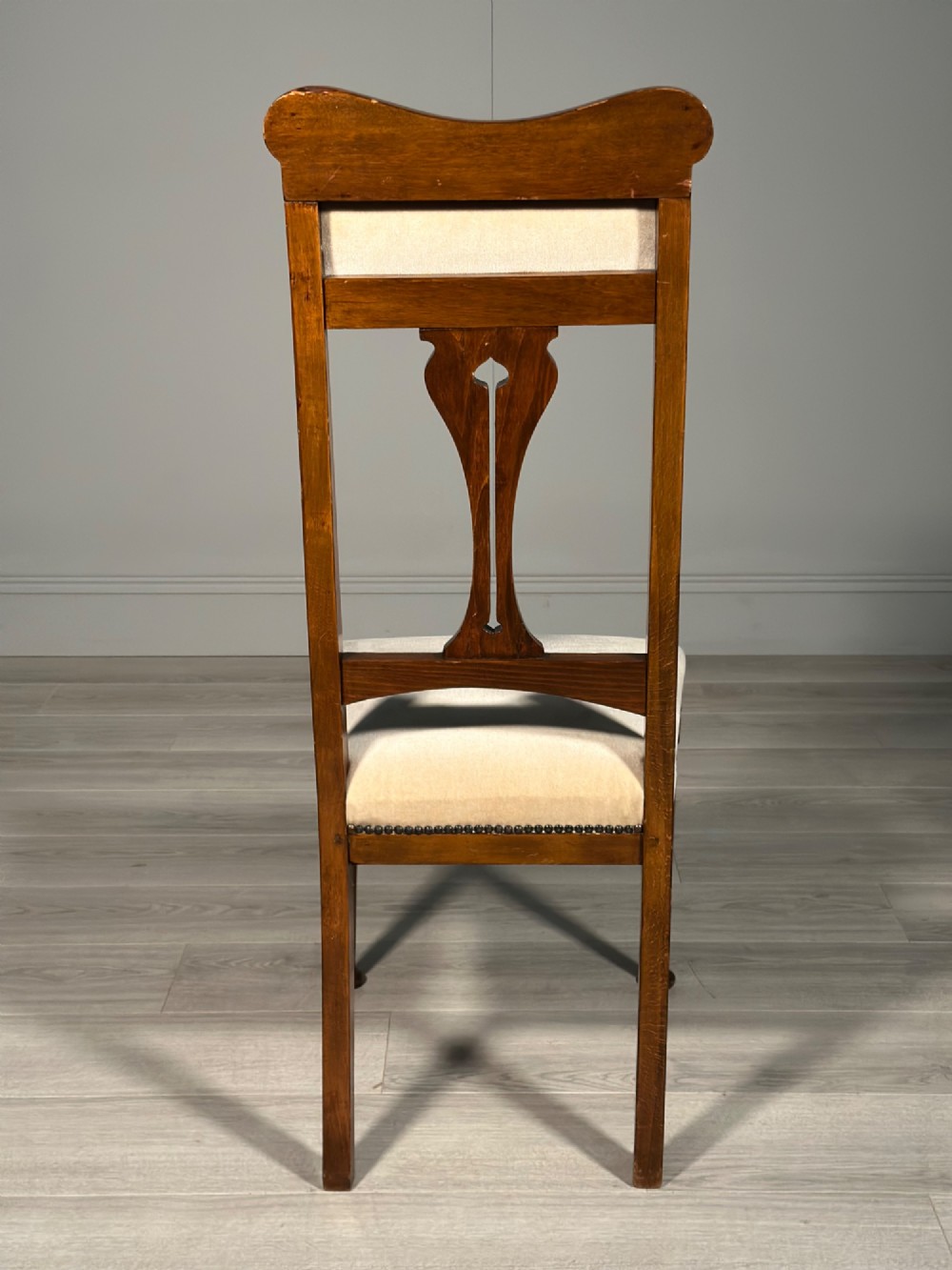 A set of four antique Biedermeier dining chairs featuring carved wooden frames, pierced back splats, and cream upholstered seats with brass stud detailing. View XIV
