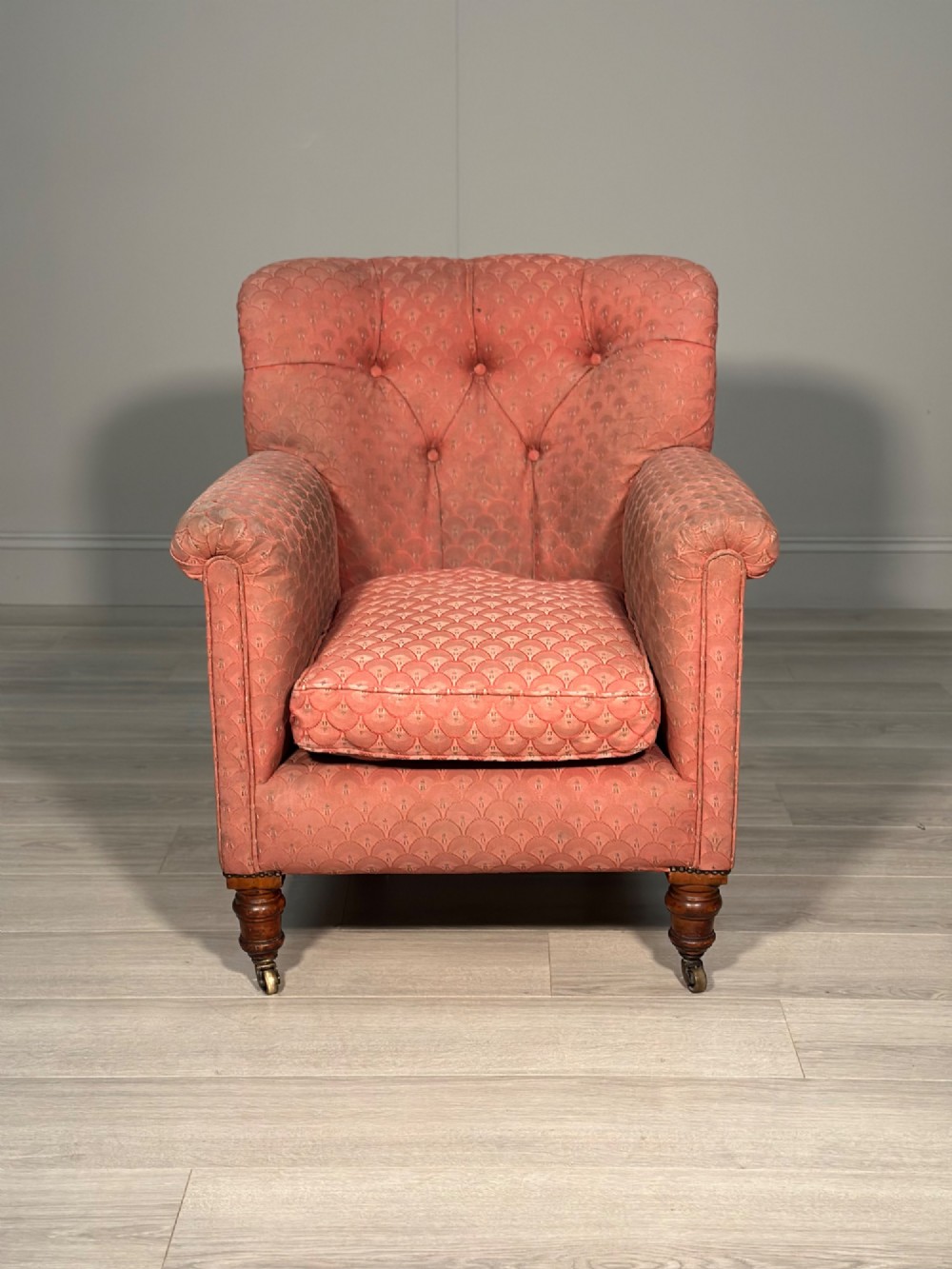 A Victorian button-back armchair upholstered in dusty pink patterned fabric with turned wooden front legs on brass castors. View II