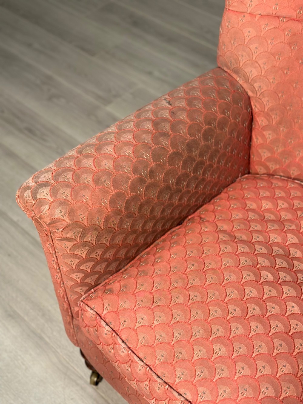 A Victorian button-back armchair upholstered in dusty pink patterned fabric with turned wooden front legs on brass castors. View IV