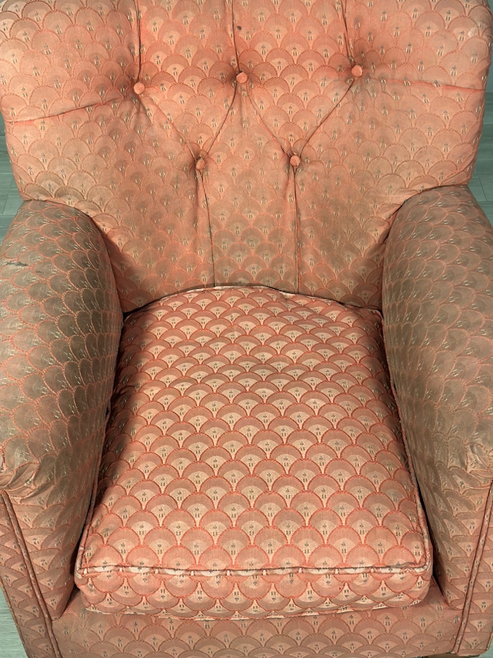 A Victorian button-back armchair upholstered in dusty pink patterned fabric with turned wooden front legs on brass castors. View V