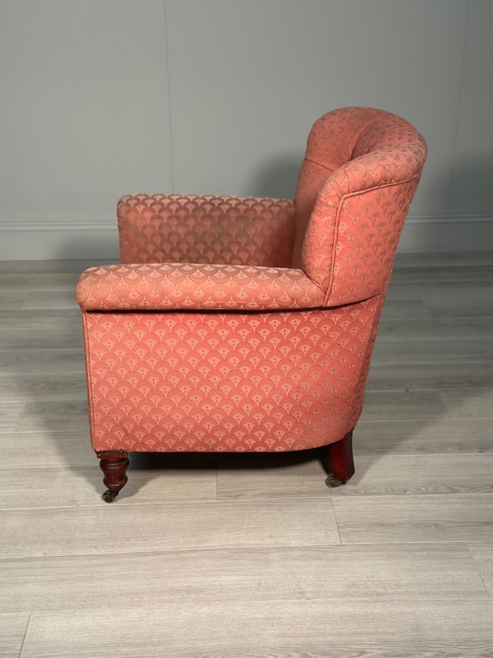 A Victorian button-back armchair upholstered in dusty pink patterned fabric with turned wooden front legs on brass castors. View VII