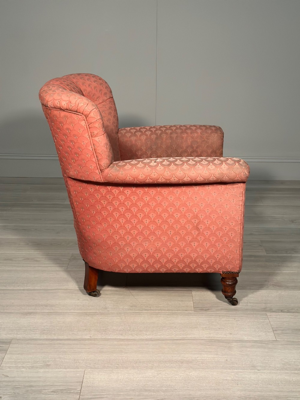 A Victorian button-back armchair upholstered in dusty pink patterned fabric with turned wooden front legs on brass castors. View IX
