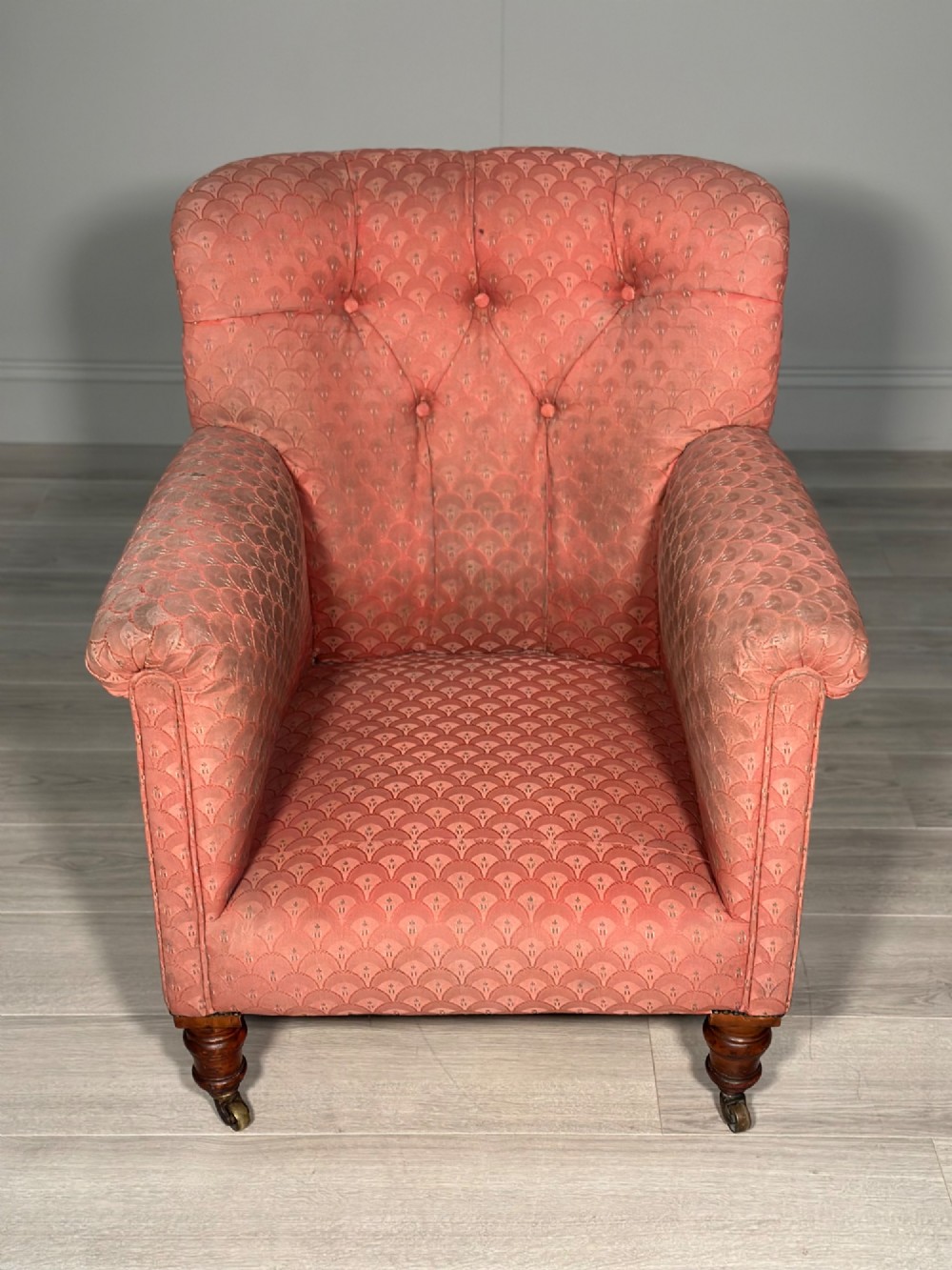 A Victorian button-back armchair upholstered in dusty pink patterned fabric with turned wooden front legs on brass castors. View XI