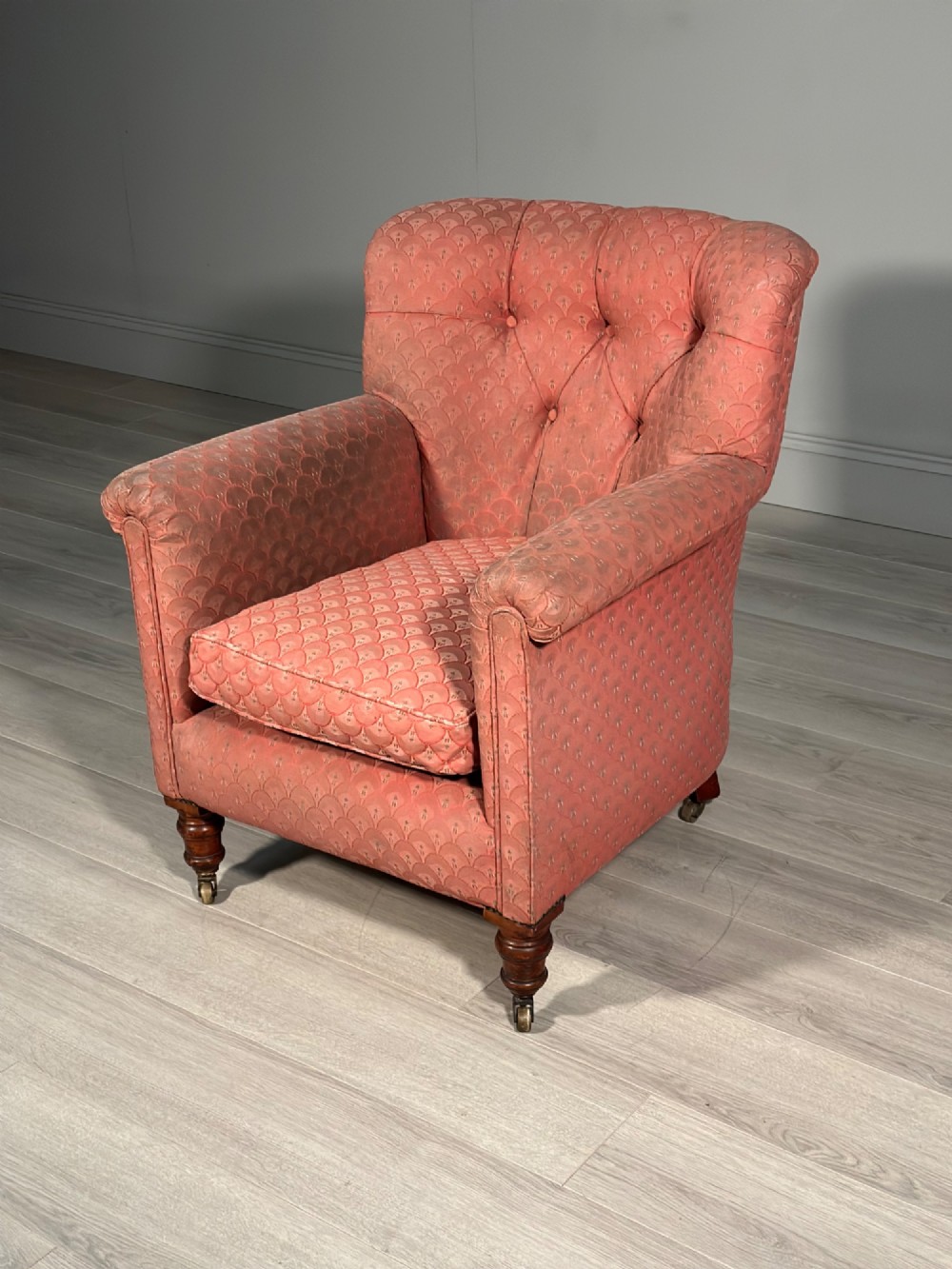 A Victorian button-back armchair upholstered in dusty pink patterned fabric with turned wooden front legs on brass castors. View XII