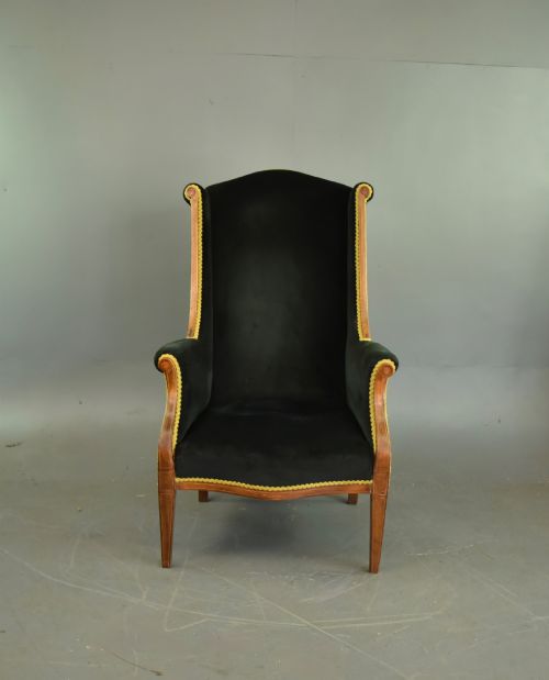 fig 1. An Edwardian mahogany wing armchair upholstered in dark green velvet with contrasting decorative gimp trim and tapered front legs.