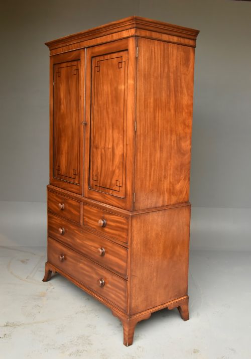 fig 1. A Georgian mahogany gentlemans wardrobe featuring a two-door upper section with ebony line inlay over a base of two short and two long drawers on bracket feet.