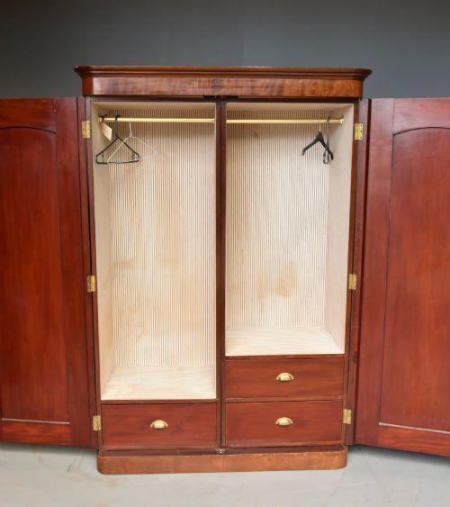 fig 1. A Victorian flame mahogany double wardrobe featuring two arched panel doors, a moulded top cornice, and a grounded plinth base.