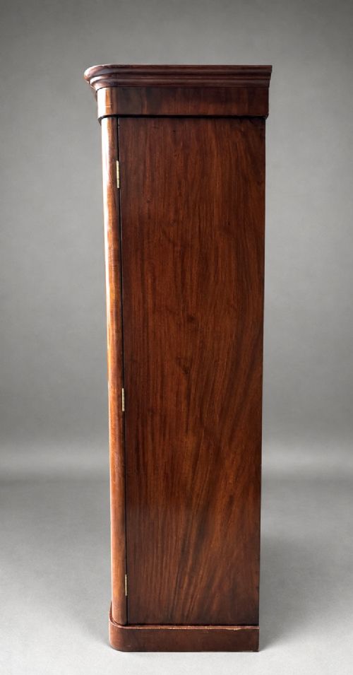 A Victorian flame mahogany double wardrobe featuring two arched panel doors, a moulded top cornice, and a grounded plinth base. View VI
