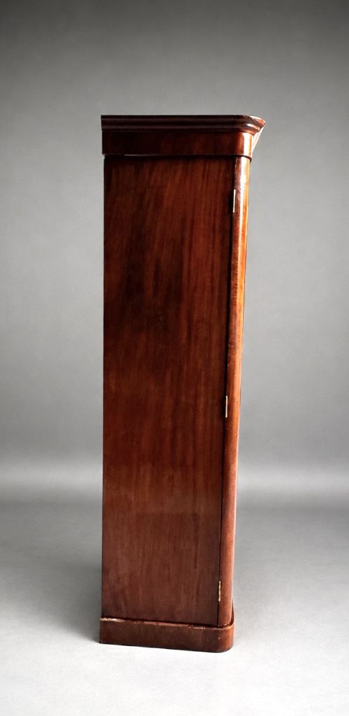 A Victorian flame mahogany double wardrobe featuring two arched panel doors, a moulded top cornice, and a grounded plinth base. View VII