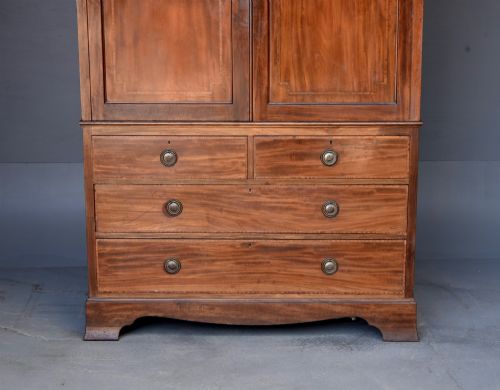 fig 1. An Edwardian flame mahogany double wardrobe featuring two panelled cupboard doors with satinwood stringing set above two short and two long drawers with brass handles.