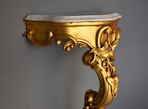 fig 1. A 19th-century Rococo Revival wall-mounted giltwood console table with a single carved support leg featuring acanthus leaf scrolls and a shaped white marble top.