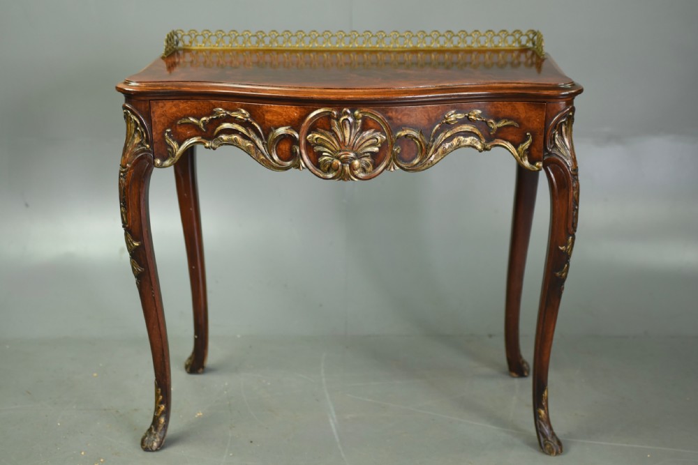 A 19th-century walnut side table with serpentine edges, ornate gilt metal mounts, cabriole legs, and a pierced brass gallery rail. View VI
