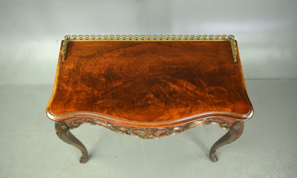 A 19th-century walnut side table with serpentine edges, ornate gilt metal mounts, cabriole legs, and a pierced brass gallery rail. View VII