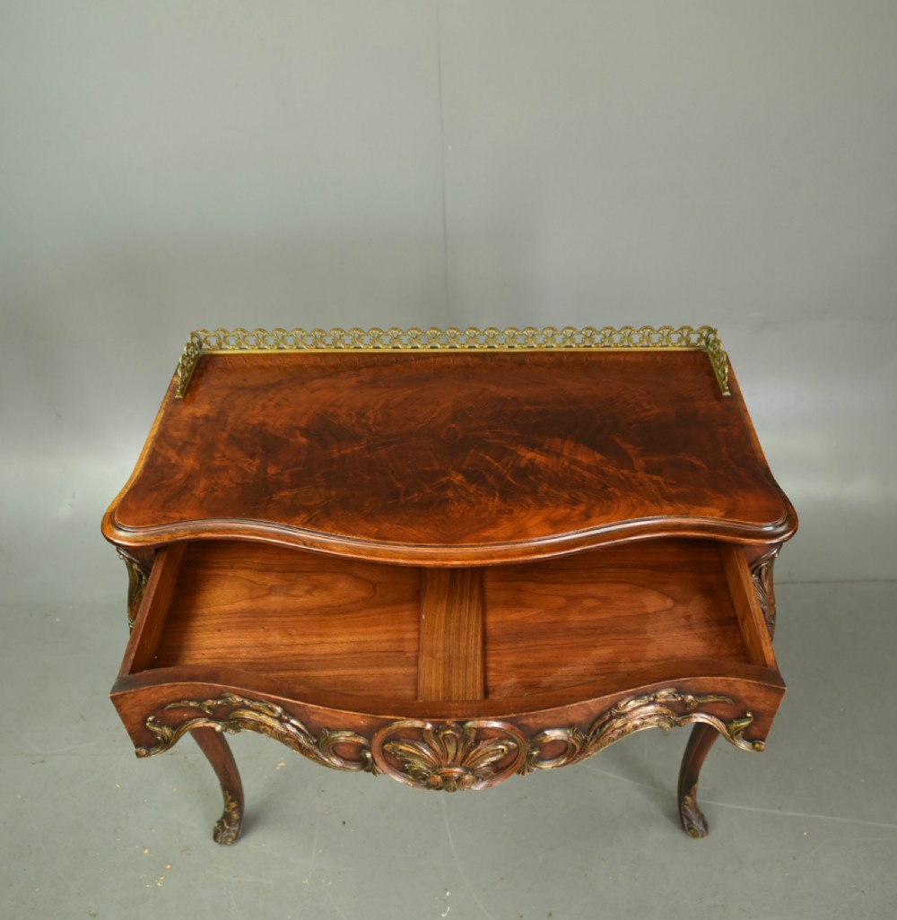 A 19th-century walnut side table with serpentine edges, ornate gilt metal mounts, cabriole legs, and a pierced brass gallery rail. View VIII