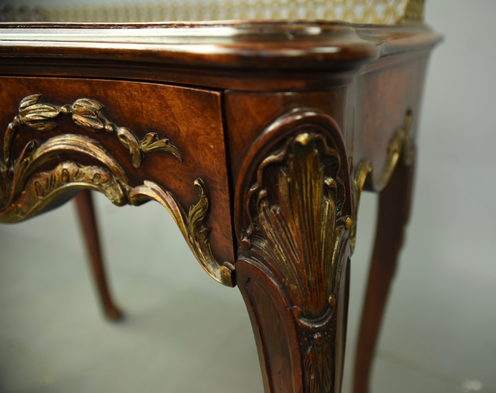 A 19th-century walnut side table with serpentine edges, ornate gilt metal mounts, cabriole legs, and a pierced brass gallery rail. View X