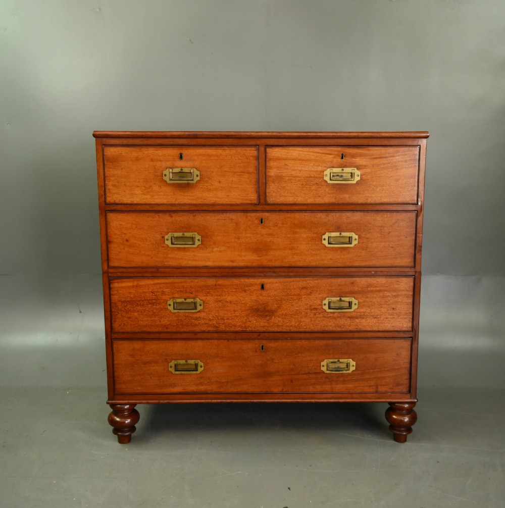 A Victorian mahogany military campaign chest featuring flush recessed brass handles, brass corner mountings, and a two-part construction resting on turned feet.