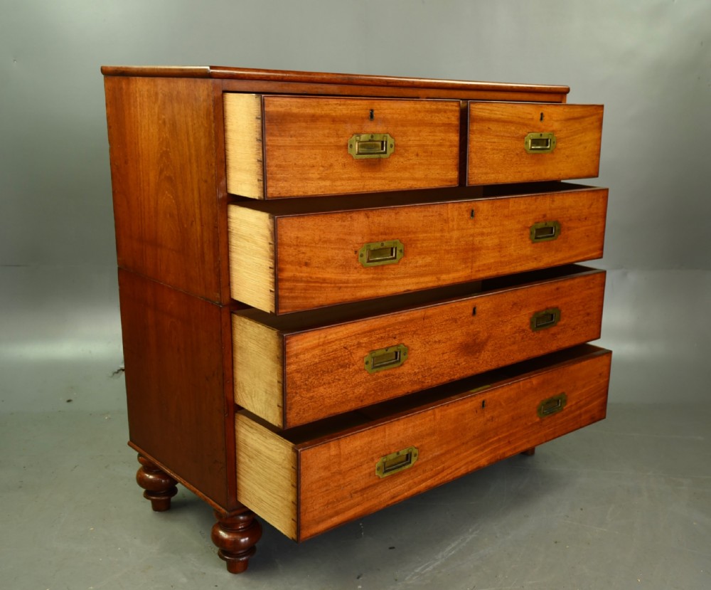 A Victorian mahogany military campaign chest featuring flush recessed brass handles, brass corner mountings, and a two-part construction resting on turned feet. View V