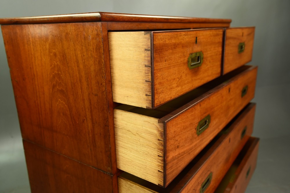 A Victorian mahogany military campaign chest featuring flush recessed brass handles, brass corner mountings, and a two-part construction resting on turned feet. View VI