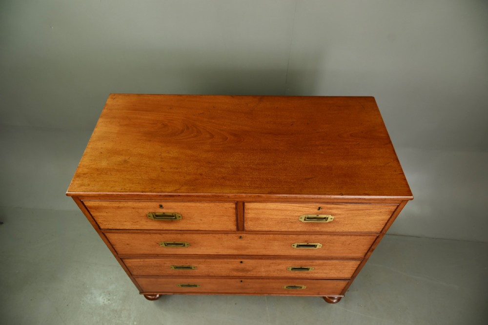 A Victorian mahogany military campaign chest featuring flush recessed brass handles, brass corner mountings, and a two-part construction resting on turned feet. View VII